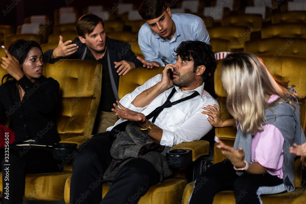 Annoying man talking on the mobile phone at the movie theater people in cinema is angry him