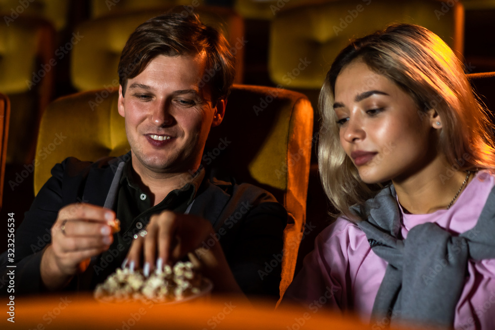 Caucasian lover enjoying to watch movie and eating popcorn together in the cinema