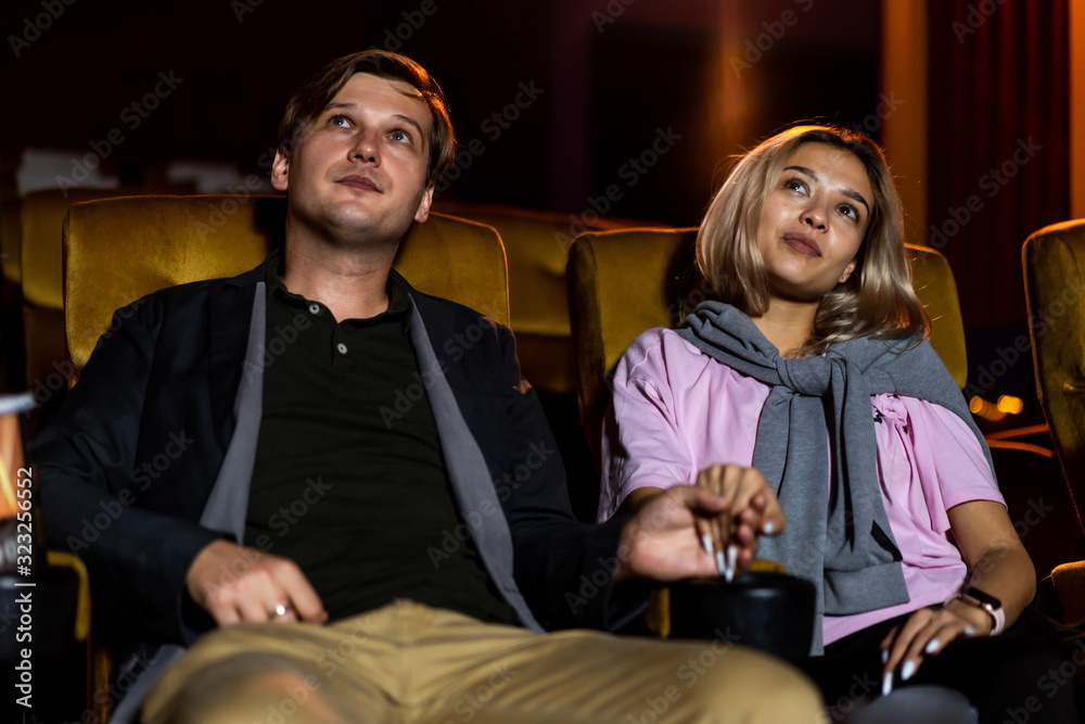 Caucasian lover enjoying to watch movie and eating popcorn together in the cinema