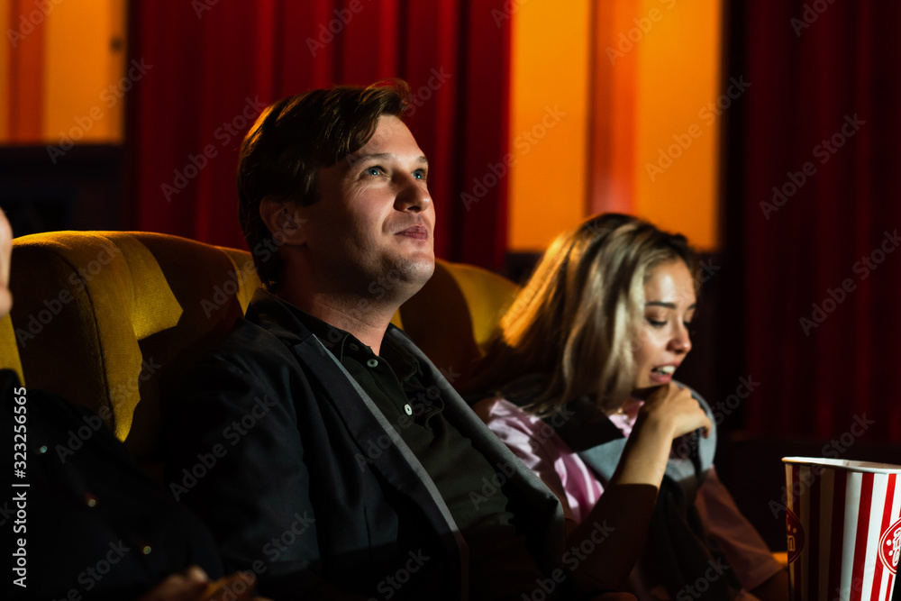 Caucasian lover and woman sitting next to them enjoying to watch movie