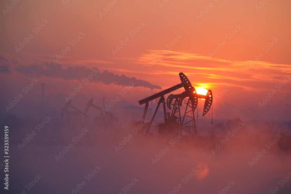 The oil pumping units by lakeside sunrise.