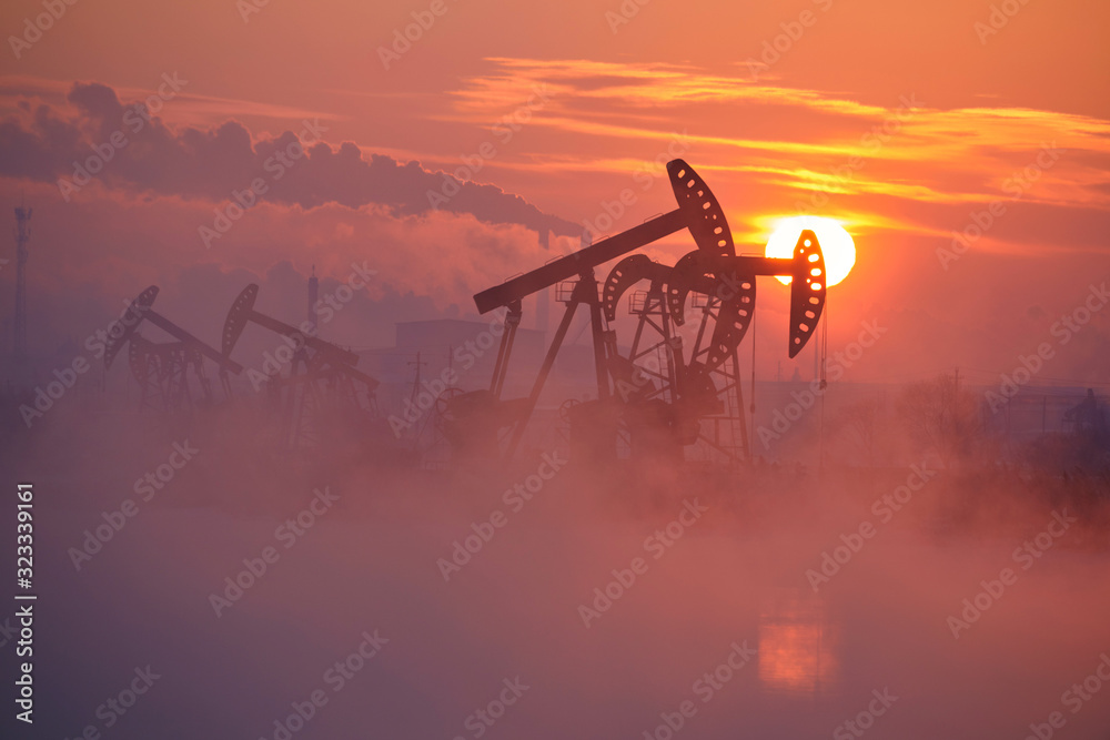 The oil pumping units by lakeside sunrise.