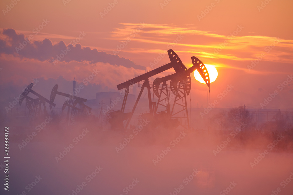 The oil pumping units by lakeside sunrise.