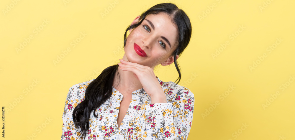 Young woman in a thoughtful pose on a yellow background