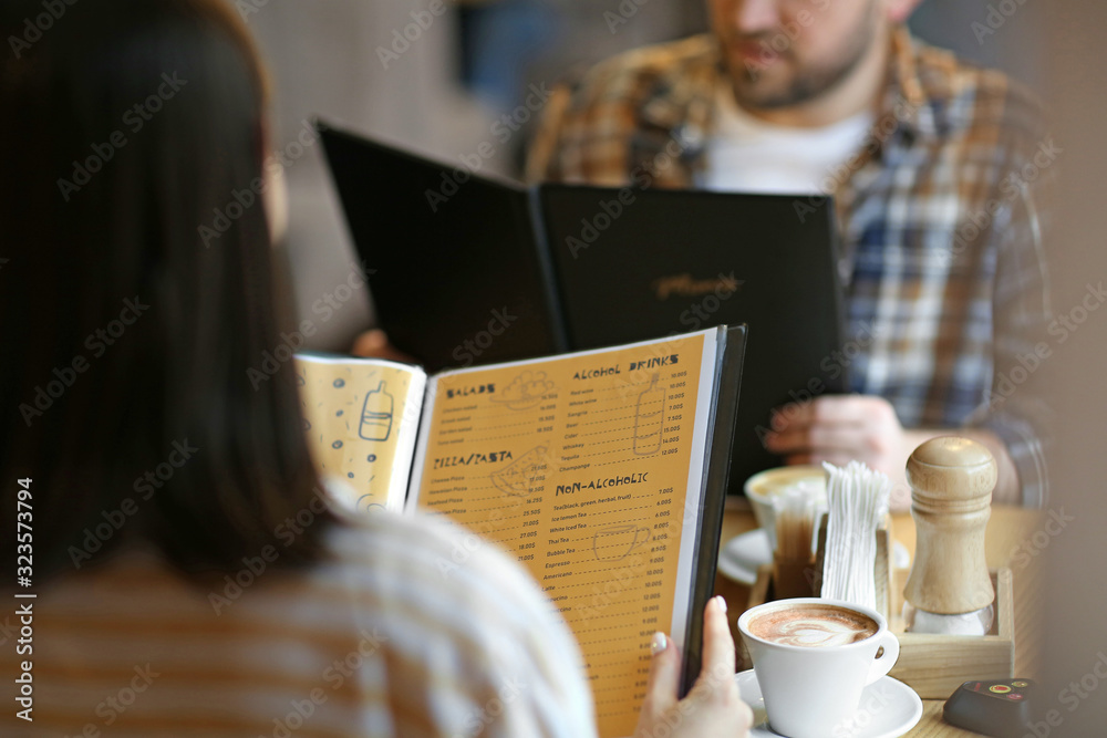 Young couple with menu sitting in restaurant