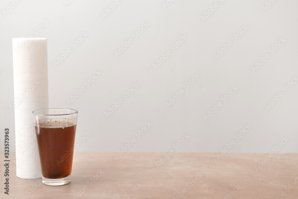 Glass with dirty water and filter on table