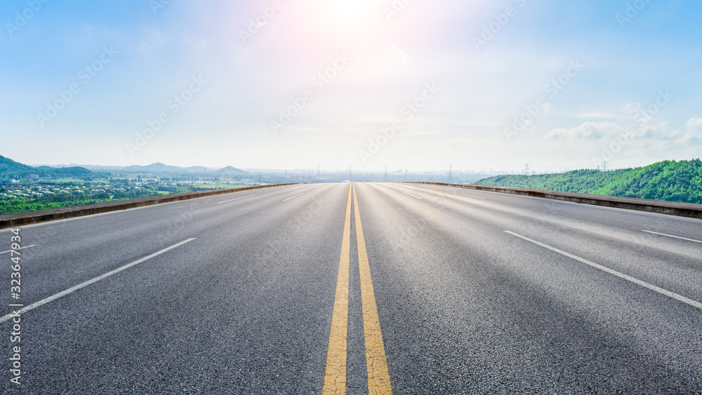 Wide asphalt highway and city suburb skyline on a sunny day in Shanghai