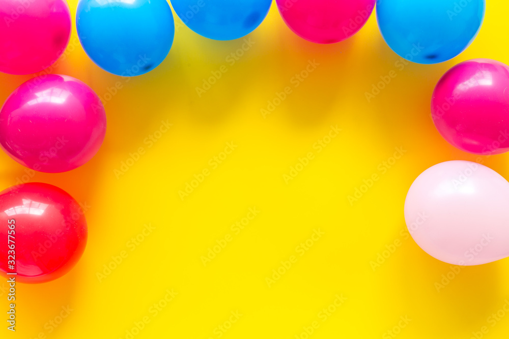 Colorful balloons frame on yellow background top-down frame copy space