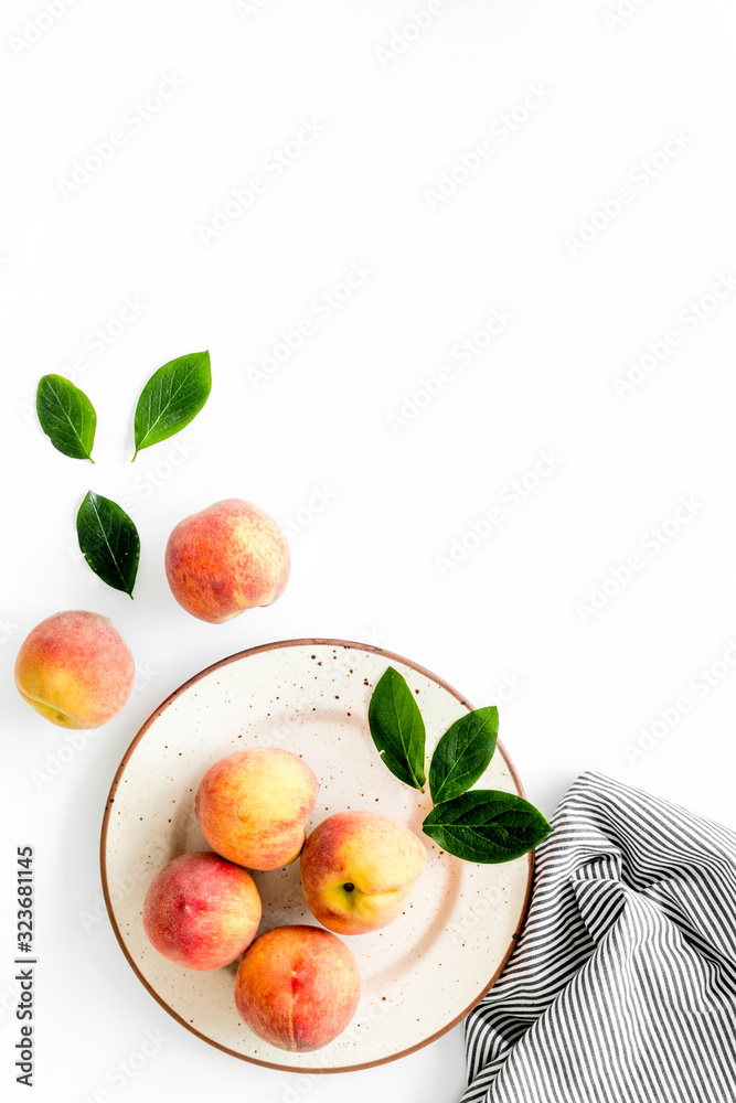 Summer lunch. Red peaches on white background with tablecloth and leaves top-down copy space