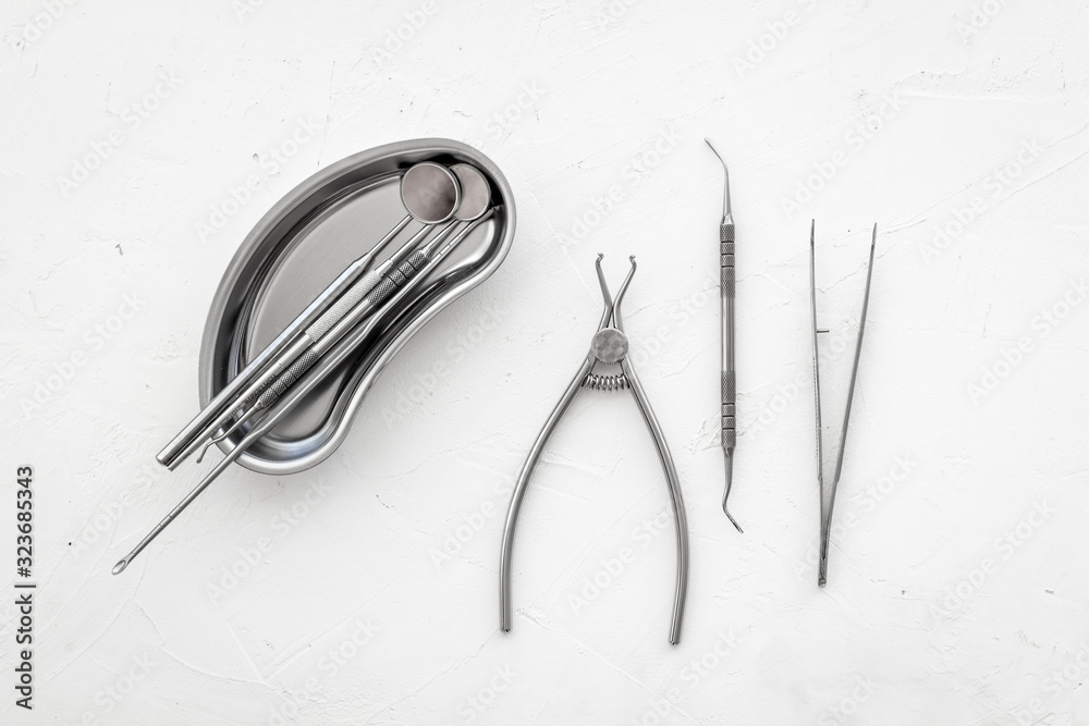 Stomatological tools in tray on dentists desk on white background top-down