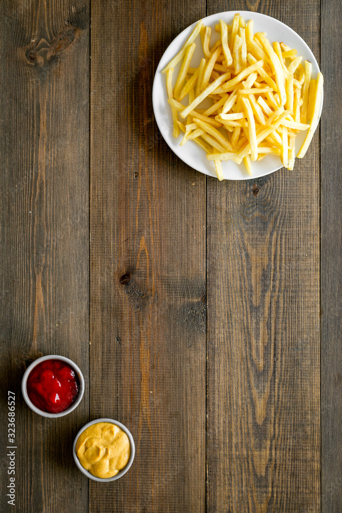 Fast food symbol. French fries on plate on dark wooden table top-down copy space