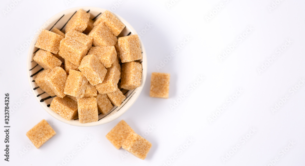 Brown sugar in a round glass cup and wooden spoon on a white background, healthy sugar is used for c