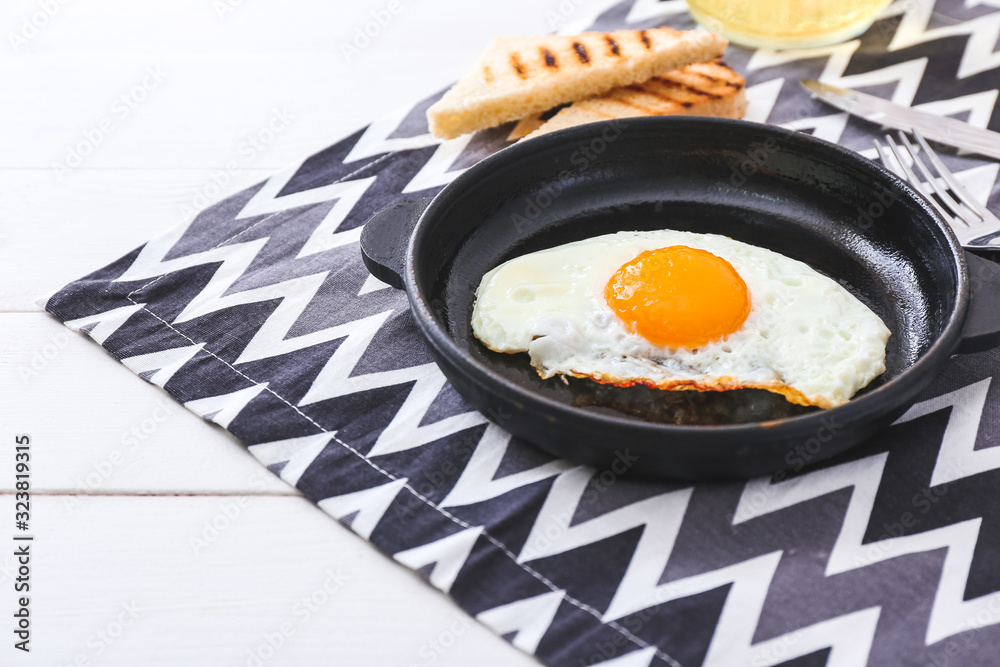 Frying pan with tasty egg on table