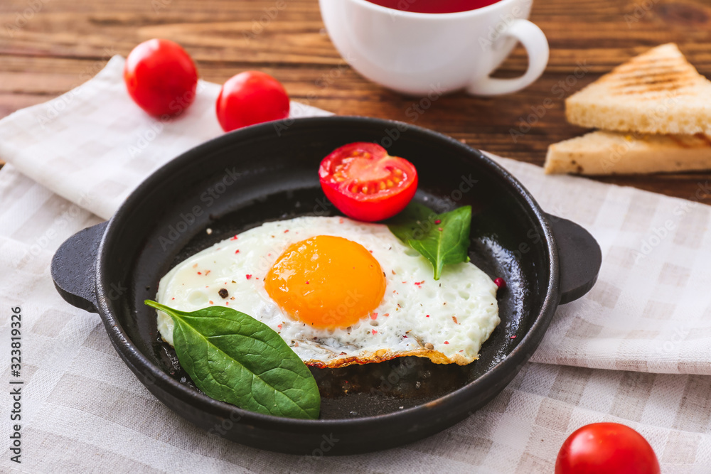 Pan with tasty fried egg, toasted bread and tomatoes on table