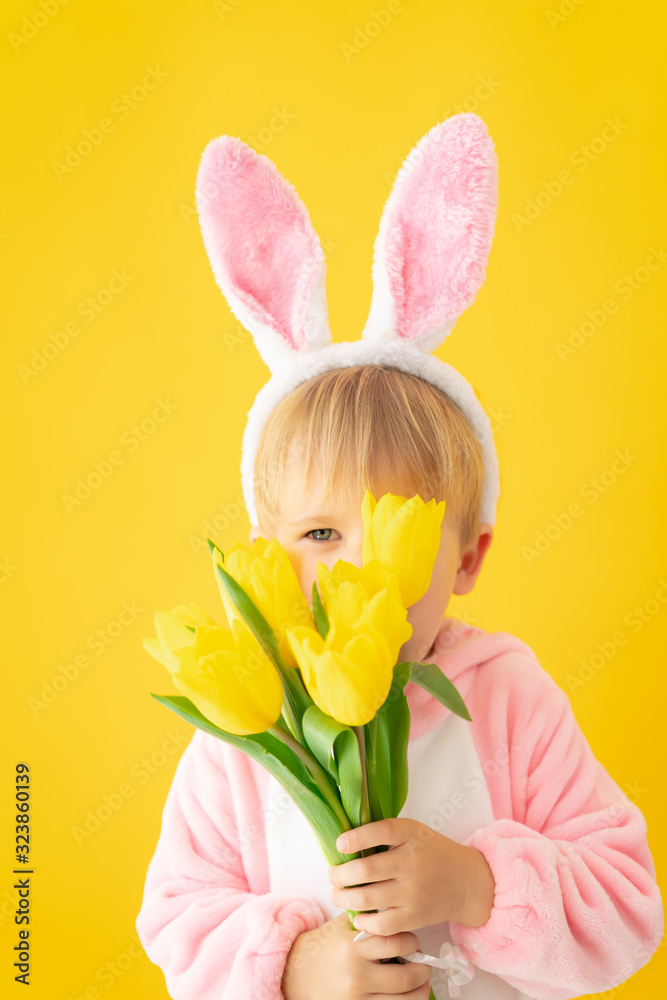 Funny kid wearing Easter bunny against yellow background