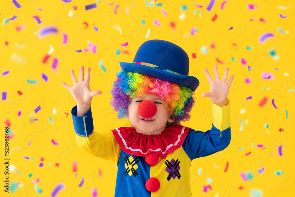 Funny kid clown playing against yellow background