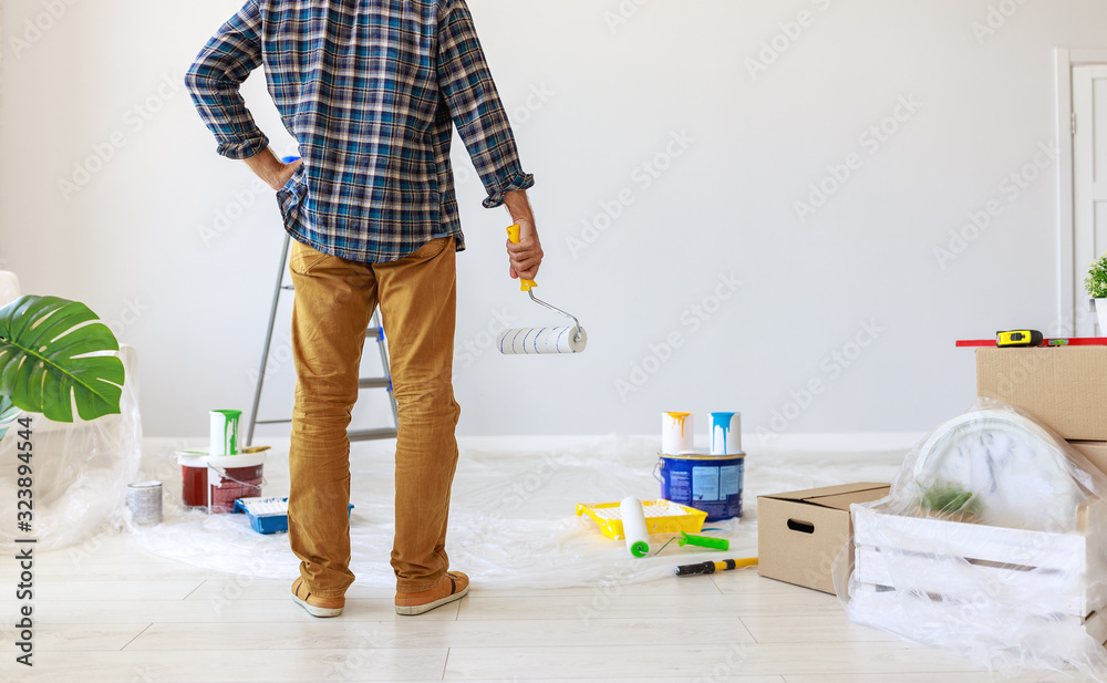 Repair in apartment. Happy man paints wall .