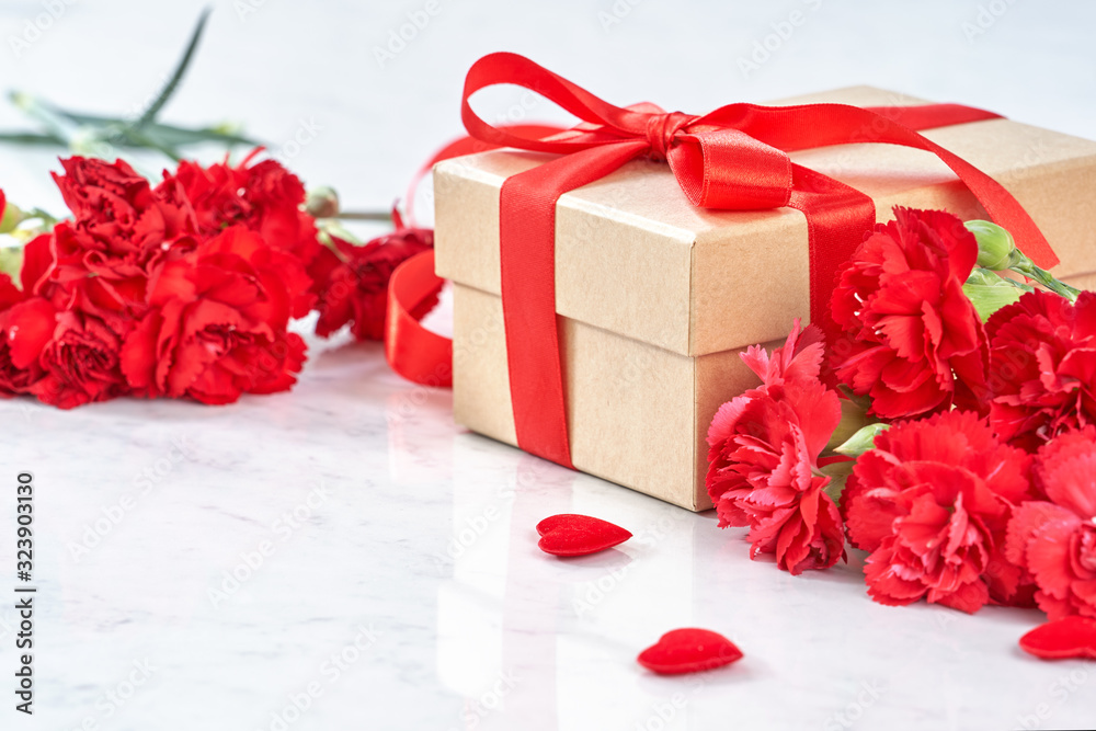 Mothers Day greeting design concept - Beautiful blooming red carnations, gift box with ribbon on wh