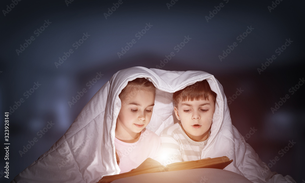 Engrossed little girl and boy reading book