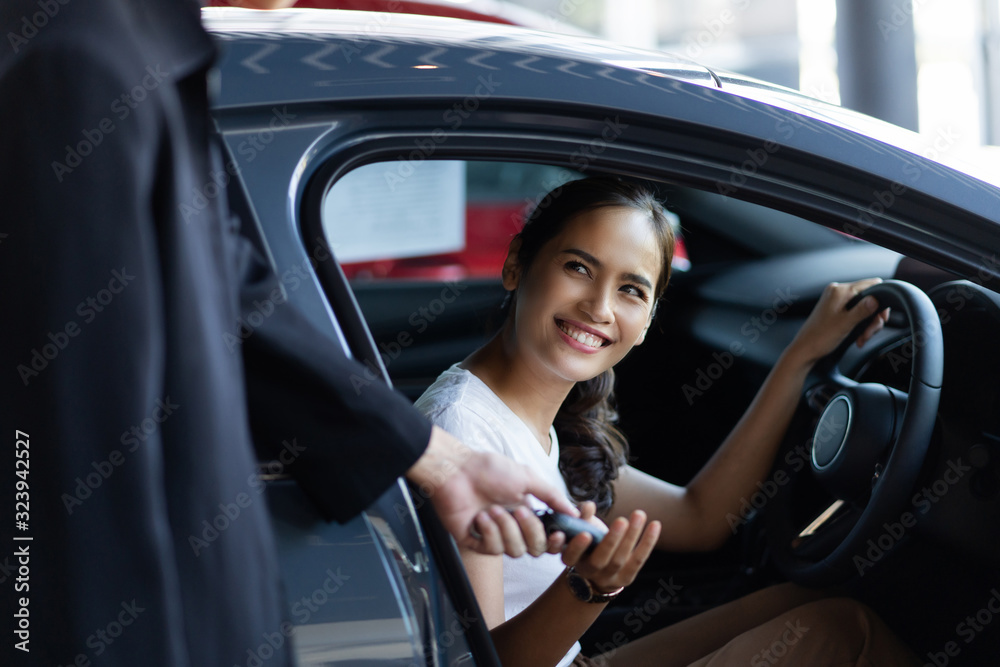 Beautiful asian woman buying a car at the showroom