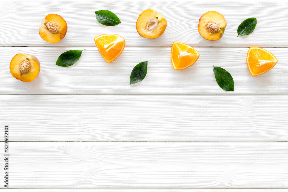 Peach slices and leaves pattern on white wooden background top-down copy space frame