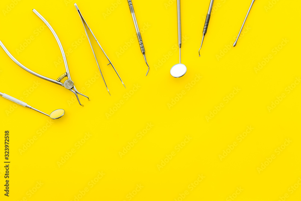 Stomatological tools on dentists desk on yellow background top-down pattern frame copy space