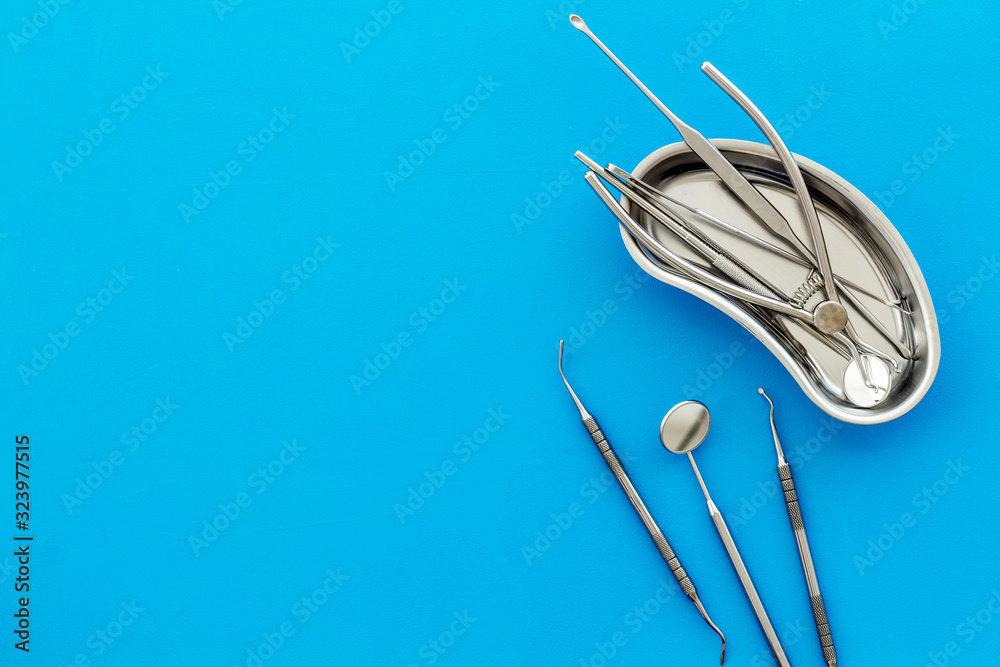 Stomatological tools in tray on dentists desk on blue background top-down space for text