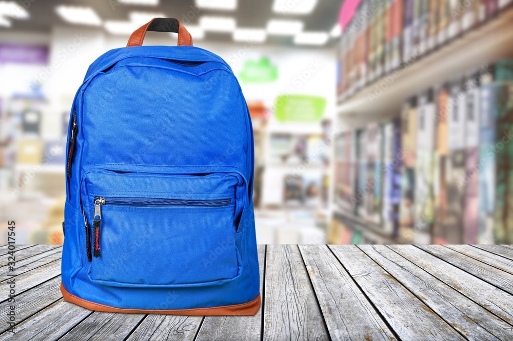 Backpack with school supplies on wooden desk