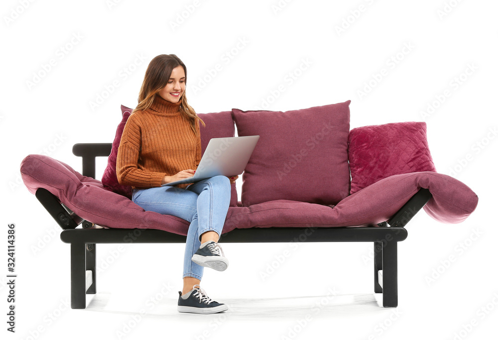 Young woman with laptop sitting on sofa against white background