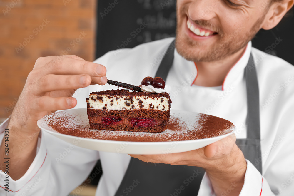 Male chef with piece of cake in kitchen, closeup