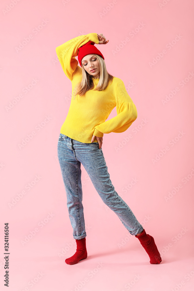 Young woman in warm sweater on color background