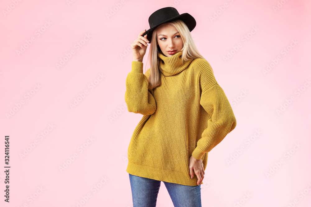 Young woman in warm sweater on color background