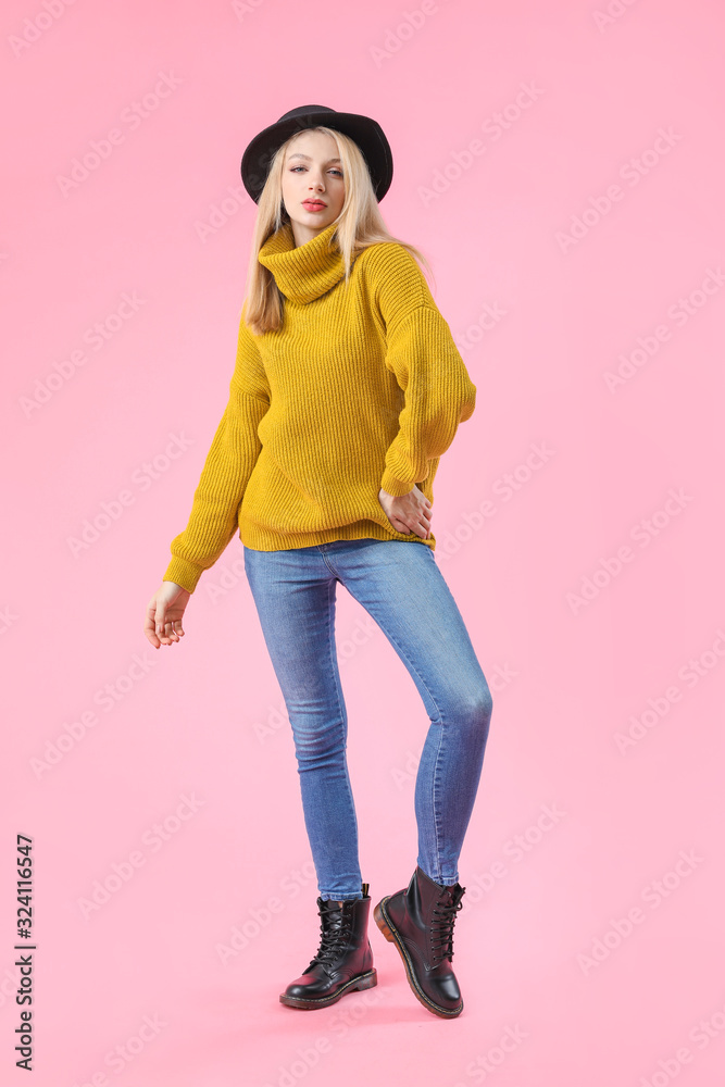 Young woman in warm sweater on color background