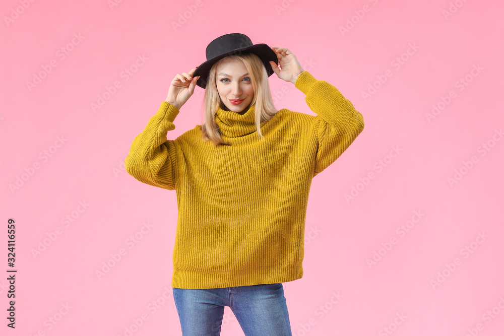 Young woman in warm sweater on color background