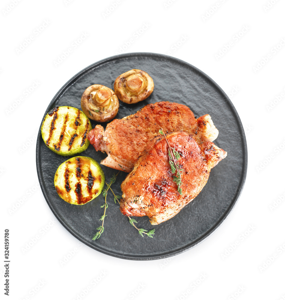 Plate with cooked pork steaks on white background