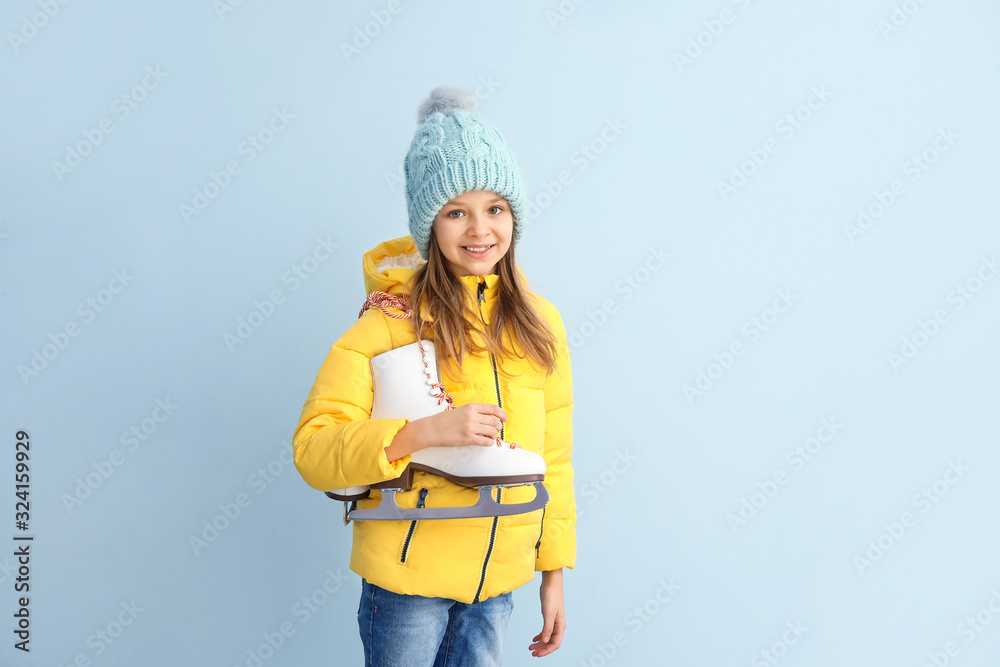 Cute little girl with ice skates on light background