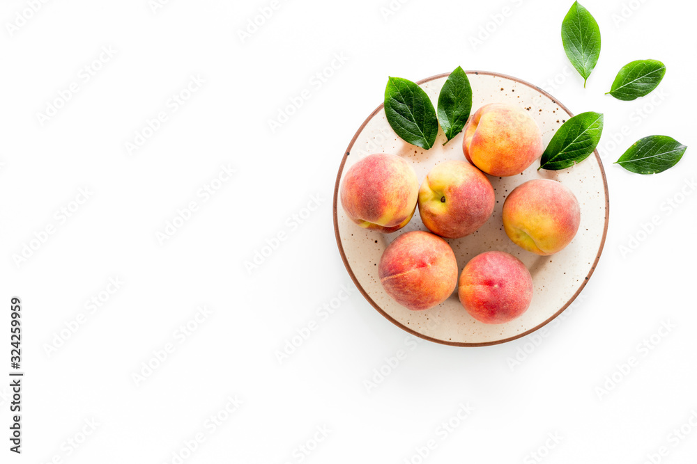 Summer fruits. Ripe red peaches on plate on white table top-down copy space