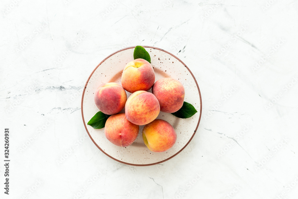 Summer fruits. Ripe red peaches on plate on white table top-down copy space