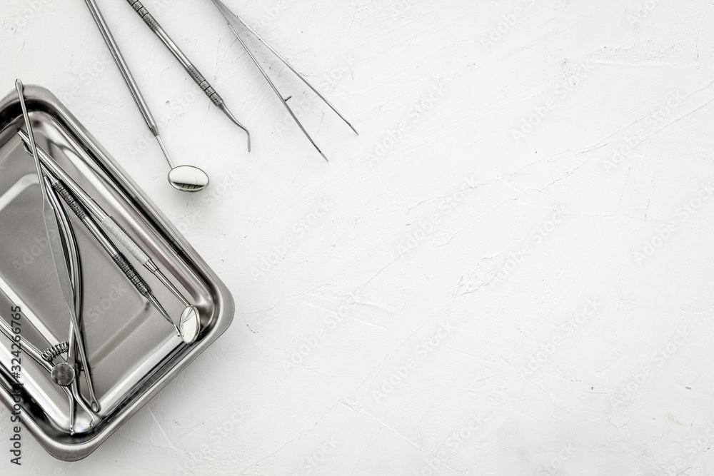 Stomatological tools in tray on dentists desk on white background top-down frame copy space