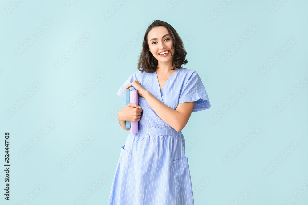 Beautiful young woman with books on color background