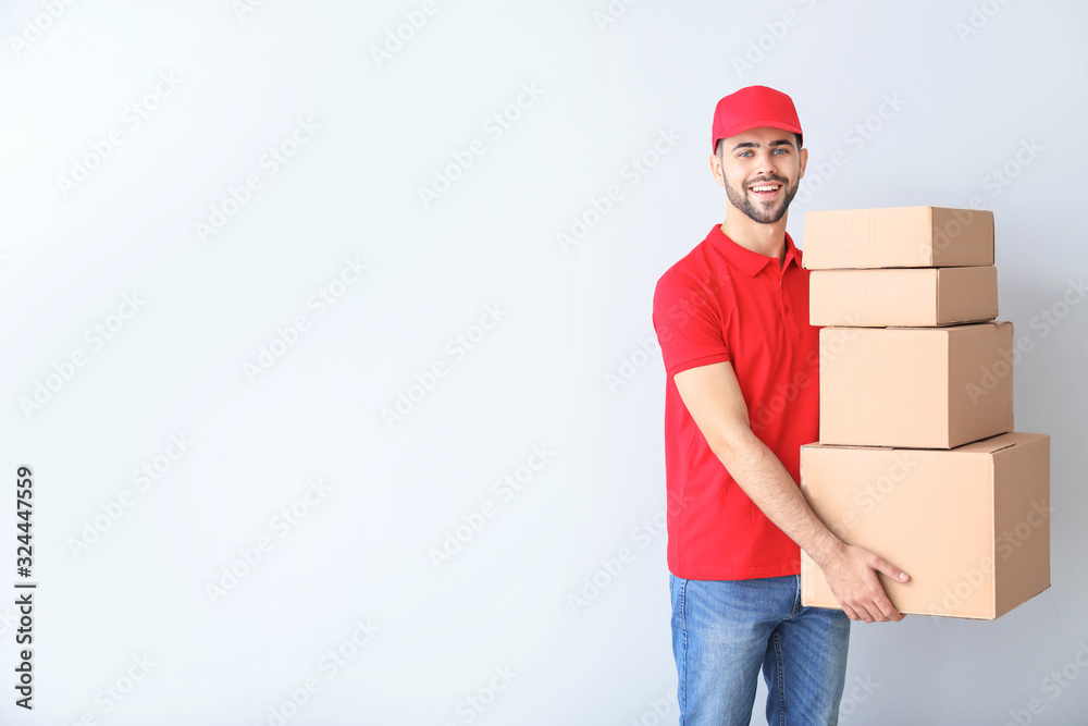 Delivery man with boxes on light background