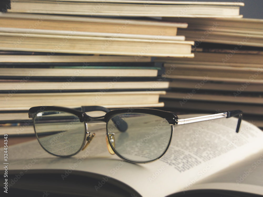 Old eyeglasses on books. Blurred letters