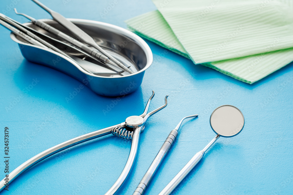 Dental instruments in stainless steel tray on blue background close up