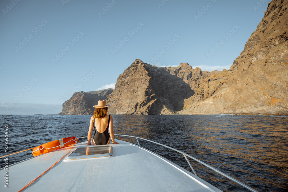 Woman enjoying ocean voyage sitting with lifebuoy on the yacht nose while sailing near the breathtak