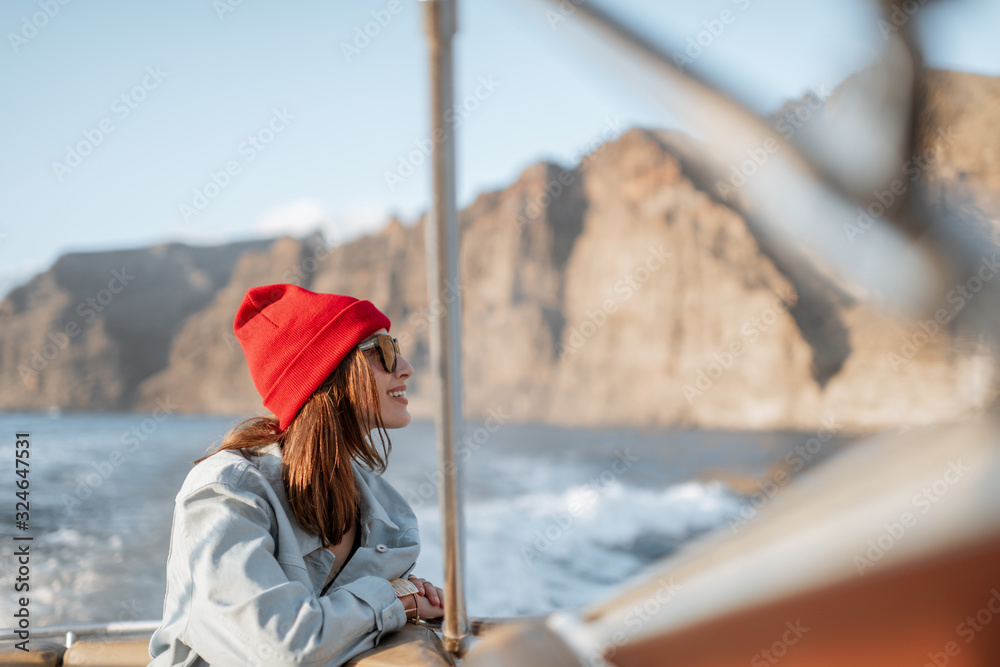 Portrait of a young woman traveler dressed casually in red hat and jeans sailing on a yacht near the