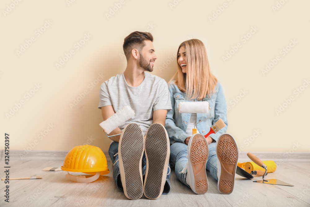 Young couple with tools resting during repair in new apartment