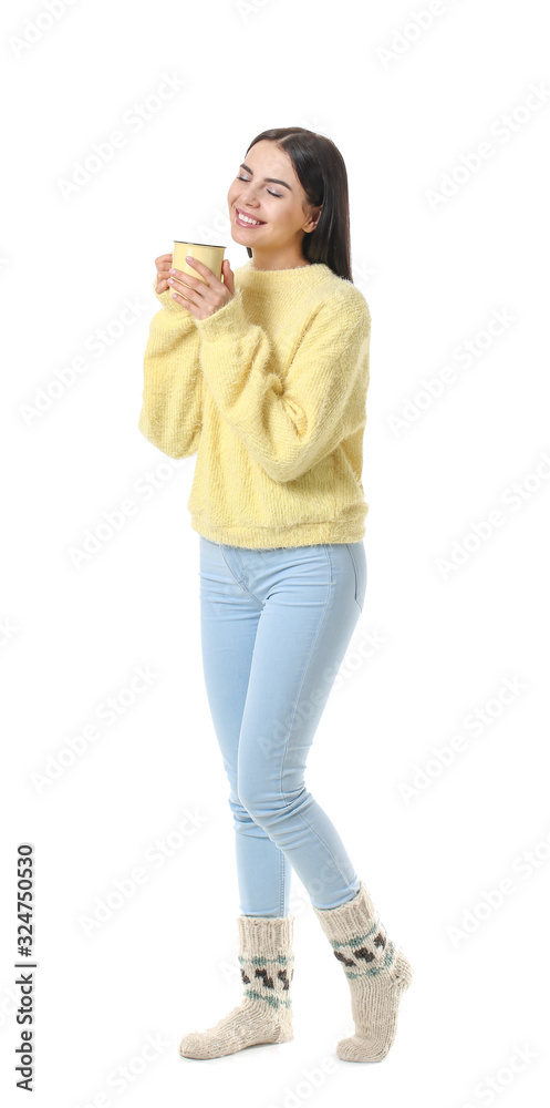 Beautiful young woman in warm sweater drinking tea on white background