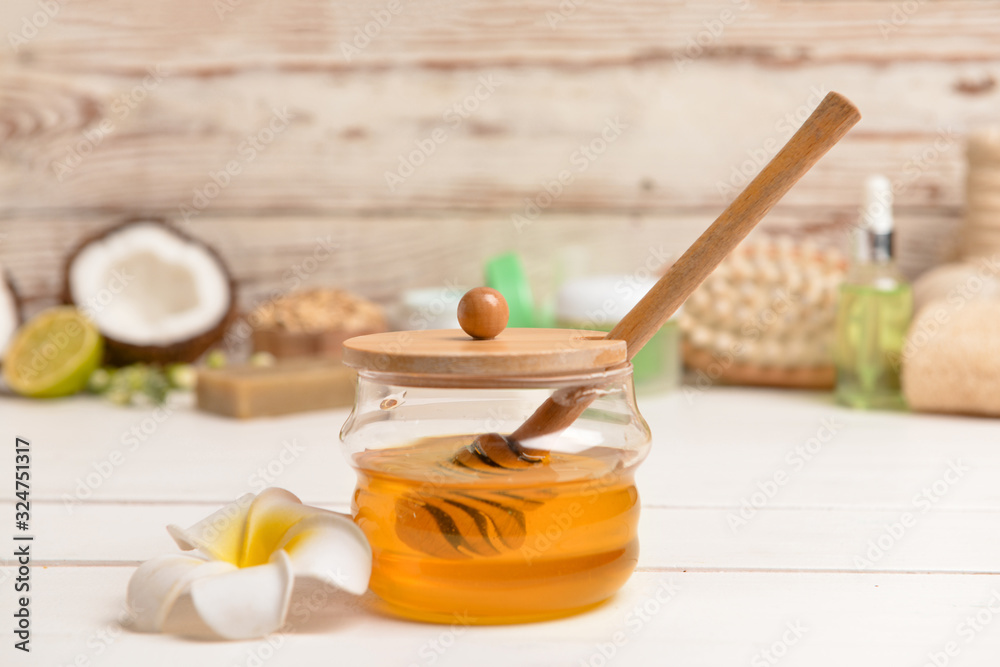 Jar with sweet honey and spa items on table