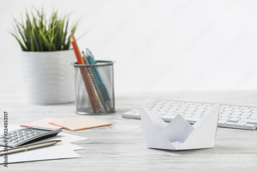 Wooden office desk with white origami boat.