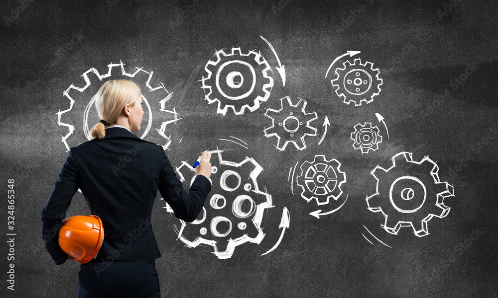 Businesswoman draws gears mechanism on blackboard